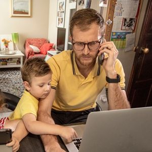 Père au téléphone et fils devant un ordinateur